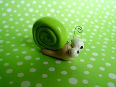 a small toy snail sitting on top of a green surface