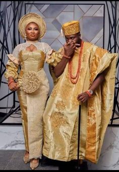 a man and woman dressed in traditional african clothing standing next to each other on a marble floor