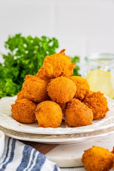 some fried food on a white plate with parsley and lemon wedges next to it