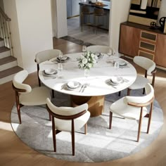 a dining room table with white chairs and plates on the top, in front of stairs