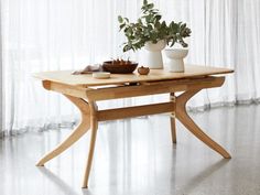 a wooden table with two white vases on it and a plant in the middle