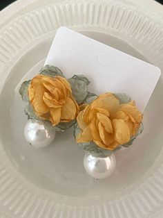 two yellow flowers and pearls are on a white plate with a card in the middle