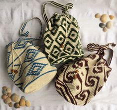 three purses sitting on top of a bed next to rocks and nuts in the background