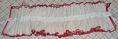 red and white ruffled bedspread sitting on top of a quilted floor