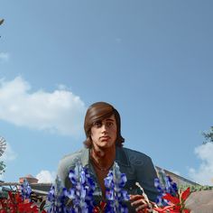 a man standing in the middle of blue and red flowers