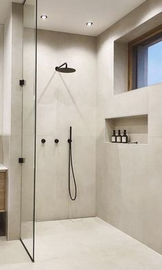 a bathroom with a walk in shower next to a sink and mirror on the wall