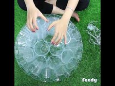 a woman sitting on the grass with her hands in an upside down plastic disc shaped object