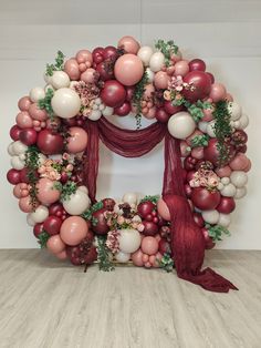 the balloon arch is decorated with red and white balloons, greenery, and flowers