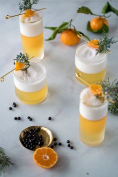 three glasses filled with drinks sitting on top of a table next to an orange slice