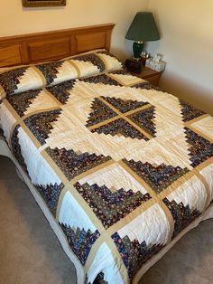 a bed with a quilt on top of it in a bedroom next to a lamp