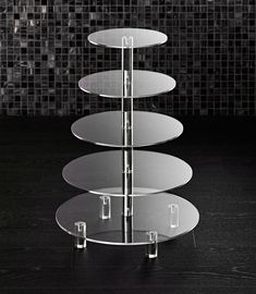 three tiered glass cake plate stand on a black table with mosaic tiles in the background