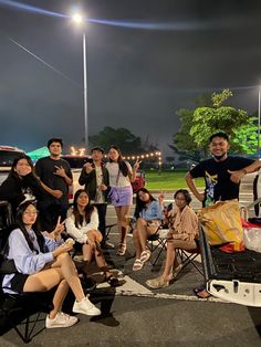 a group of people sitting in chairs on top of a parking lot next to each other