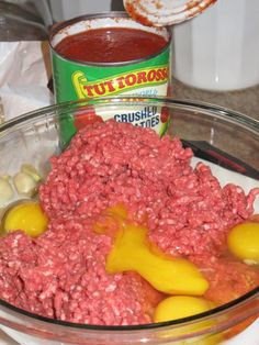 ground beef, mustard and garlic in a bowl next to a can of tomato sauce