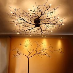 a living room with a tree painted on the ceiling and lights hanging from the ceiling