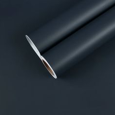 a roll of black paper with a white edge on a dark surface, close up