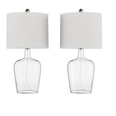 two clear glass table lamps with white shades on each lamp, one is turned off and the other has a white shade