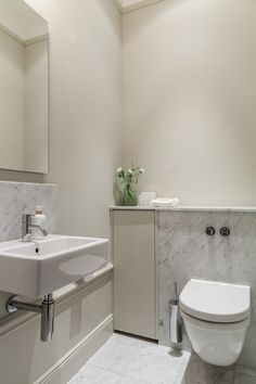 a white toilet sitting next to a sink in a bathroom