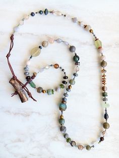 Rugged and elegant, coastal and timeless. Perfect for all year around. This piece includes quality gemstones like Prehnite, Boulder Opal, Labradorite, Jade, Moonstone, Agates, Ocean Jasper, and more. Stones in a variety of sizes, finish, and texture. Unique and stunning. Mix in Ancient Roman Glass, Recycled Glass, bone beads, jagged coconut coconut disks, mixed metals, coconut disks, shell beads, Mother of Pearl shell, and more. Distressed leather loop and wood stick button closure which is exte Ancient Roman Glass, The Cliff, Roman Glass, Multi Strand Bracelet, Bone Beads, Beach Inspired, Ancient Romans, Ocean Jasper, Shell Beads