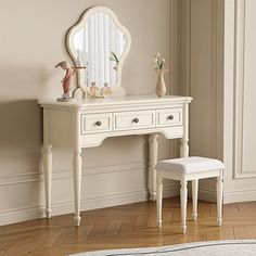 a white dressing table with a mirror and stool next to it on a hard wood floor