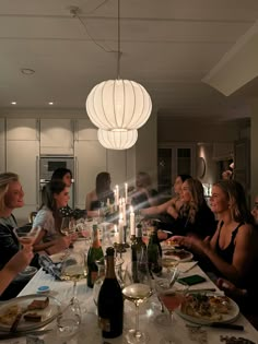 a group of people sitting around a dinner table with food and wine glasses on it