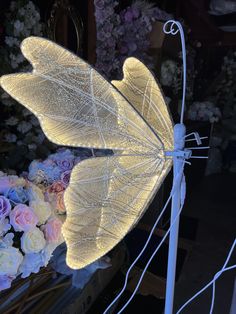 a white lighted dragon sitting on top of a metal stand next to flowers and plants