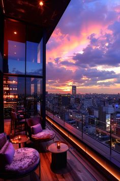 a balcony with chairs and tables overlooking the city at sunset or dawn, in an urban setting