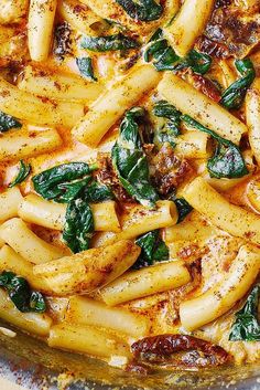 pasta with spinach and sauce in a pan on a wooden table, ready to be eaten