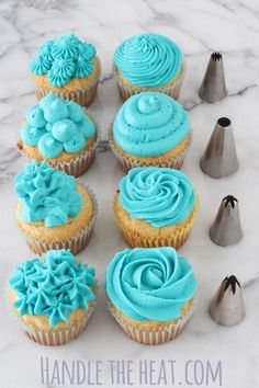 cupcakes with blue frosting and icing are arranged on a marble surface