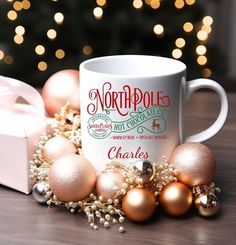 a white coffee mug sitting on top of a wooden table next to christmas ornaments and a box