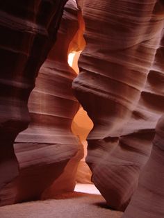 a narrow slot in the side of a canyon with light coming from it's opening