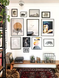 a living room filled with lots of framed pictures on the wall above a coffee table