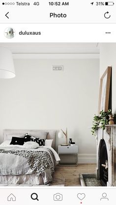 a white bedroom with a fireplace and bed in the corner, next to a mirror