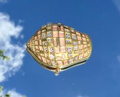 a close up view of a gold and diamond purse in the sky with clouds behind it