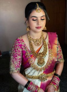 a woman in a pink and white sari with gold jewelry on her neck,