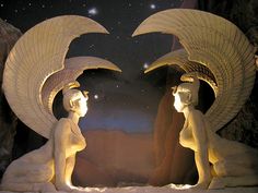 two statues sitting next to each other in front of a night sky