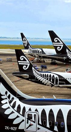 several black and white jetliners sitting on top of an airport tarmac next to the ocean