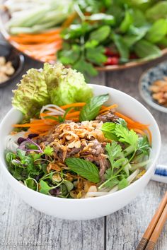 a white bowl filled with lots of different types of food next to chopsticks