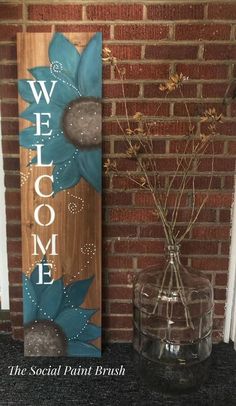 a wooden sign that says welcome to the social paint brush and vase with flowers in it