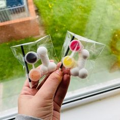 a person holding three small plastic objects in front of a window