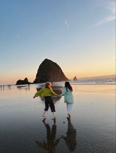 two girls are walking on the beach at sunset with their arms around each other and one girl is holding her hand out