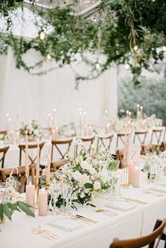 the tables are set with white flowers and greenery for an elegant wedding reception in a tented area