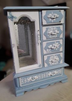 an old blue and white dresser with mirror on it's top, sitting on a table