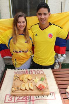 two people standing in front of a table with food on it and flags behind them