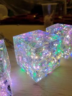 three glowing cubes sitting on top of a wooden table next to eachother