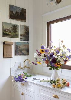 a vase filled with flowers sitting on top of a white counter next to a window