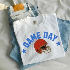 Introducing our Game Day Football Shirt for Women, the ultimate retro sports football shirt for game day! This Football Tshirt features a classic football helmet design, perfect for showing your love for the game. Made with Comfort Colors Graphic Tee, this shirt is not only stylish but also comfortable to wear all day long. Whether you're headed to the stadium or watching the game from the comfort of your own home, this shirt is a must-have for any football fan. So, gear up for game day and show your support for your favorite team with this Game Day Football Shirt! THE SHIRT Comfort Colors 1717 Unisex Jersey Short Sleeve 100% Ringspun Soft Cotton Fits True To Size Size UP 1-2 Sizes For An Oversized Look CUSTOMIZE IT  Want a different color or design? Shoot USA message :) Thanks for support Football Graphic Tees, Football Helmet Design, Football Graphic Tee, Game Day Football, Football Game Outfit, Retro Sports, Retro Football, Helmet Design, Sports Football