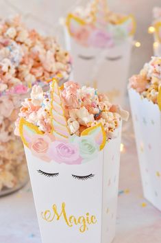 two unicorn popcorn boxes filled with pink and yellow sprinkles on top of a table