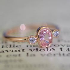 a pink diamond ring sitting on top of an open book with the word love written in it