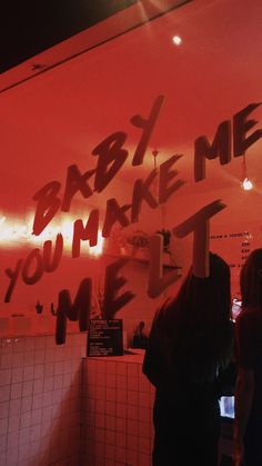 people standing in front of a red wall with writing on it that says baby, me you make me feel me