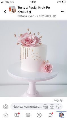 a white cake with pink flowers on top and gold sprinkles around it